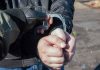 Gloved officer handcuffing a person's hands outdoors