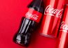Coca-Cola bottles and cans on red background