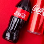 Coca-Cola bottles and cans on red background