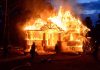House engulfed in flames with firefighters present