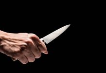Hand holding a knife against a black background