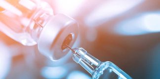 Syringe drawing liquid from a vial