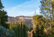 Hollywood sign on hill surrounded by trees and buildings.