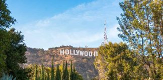 Hollywood sign on hill surrounded by trees and buildings.