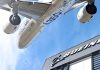Airbus plane flying over Boeing building.