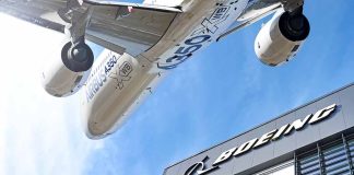 Airbus plane flying over Boeing building.