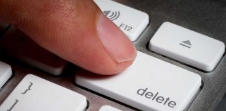 Finger pressing a delete key on keyboard