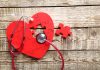 Red heart puzzle with stethoscope on wooden background