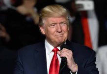 Trump holding microphone wearing suit and red tie