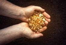 Hands holding gold nuggets over dark background