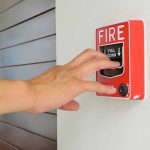 Hand reaching to pull fire alarm lever