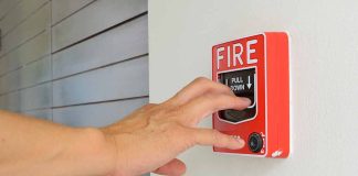 Hand reaching to pull fire alarm lever