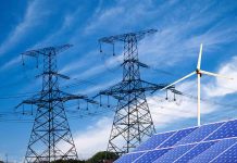 Power lines solar panels and wind turbine against sky
