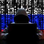 Hacker in hoodie with Russian flag background and code