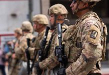 Soldiers in camouflage standing in a line with rifles