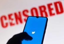 Phone displaying Twitter app with CENSORED in background