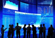 Silhouetted people in front of stock market displays