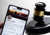 Smartphone displaying Twitter profile beside a judge gavel