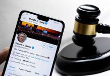 Smartphone displaying Twitter profile beside a judge gavel