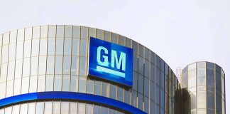 Glass building with large GM logo on top.