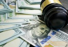 Gavel and hundred dollar bills on table