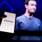 Phone displaying Meta logo in front of presentation