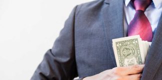 Person in suit putting dollars in jacket pocket