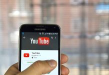 Hand holding smartphone with YouTube app open