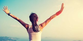 Person with arms raised overlooking a scenic view