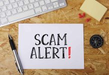Scam alert message on a wooden desk.