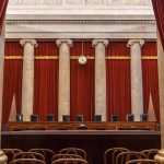 Empty courtroom with columns red curtains and chairs
