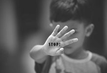 Child holding up hand with STOP written on palm