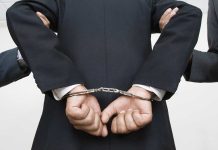 Person handcuffed in suitescorted by two others