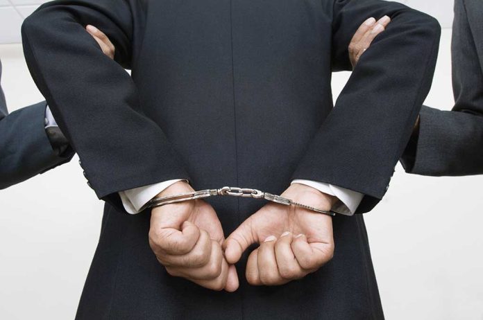 121141399 featured image Person handcuffed in suitescorted by two others