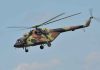 Camouflage military helicopter in flight against blue sky