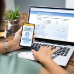 Person using phone and laptop for online banking