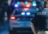 Police officer with patrol car and flashing lights