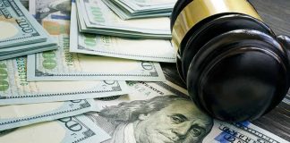 Gavel and hundred dollar bills on table