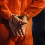 Person in orange jumpsuit with handcuffs behind back