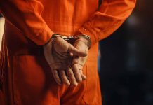 Person in orange jumpsuit with handcuffs behind back
