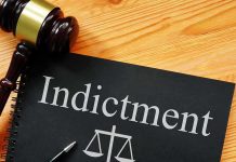 Gavel next to indictment document on wooden table