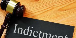 Gavel next to indictment document on wooden table