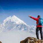 Hiker with arms outstretched in front of snowy mountains