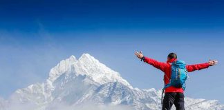 Hiker with arms outstretched in front of snowy mountains