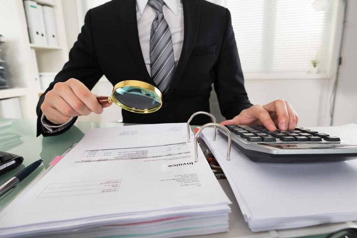 396395584 featured image Person examining documents with magnifying glass and calculator.