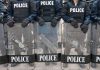 Police officers in riot gear holding shields