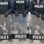 Police officers in riot gear holding shields