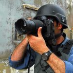 Person in helmet taking photos with a large camera