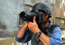 Person in helmet taking photos with a large camera