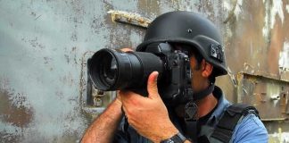 Person in helmet taking photos with a large camera
